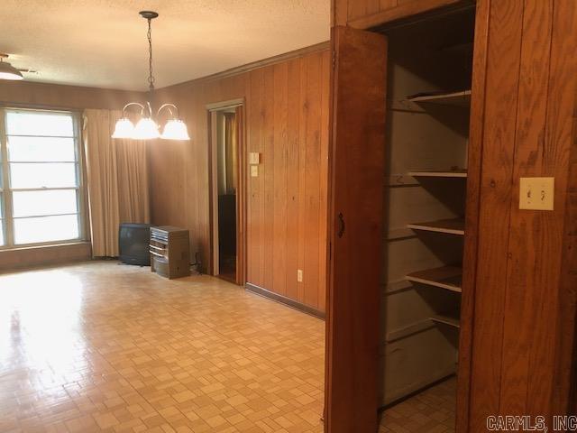 unfurnished dining area with wooden walls and an inviting chandelier