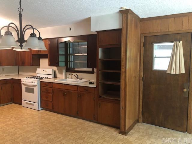 kitchen featuring a sink, white gas range oven, light countertops, light floors, and a chandelier