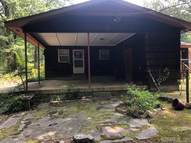 rear view of property with an attached carport and covered porch