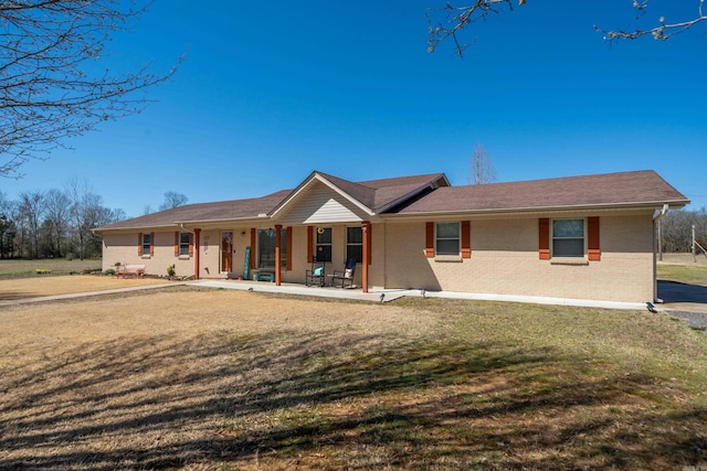 view of front of house featuring brick siding, a porch, and a front lawn