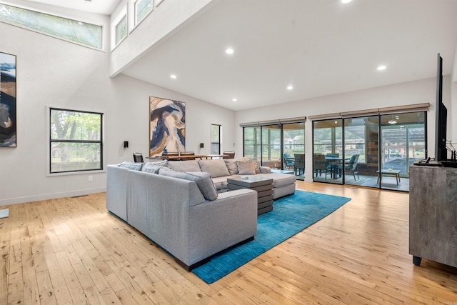 living area with recessed lighting, high vaulted ceiling, baseboards, and wood-type flooring