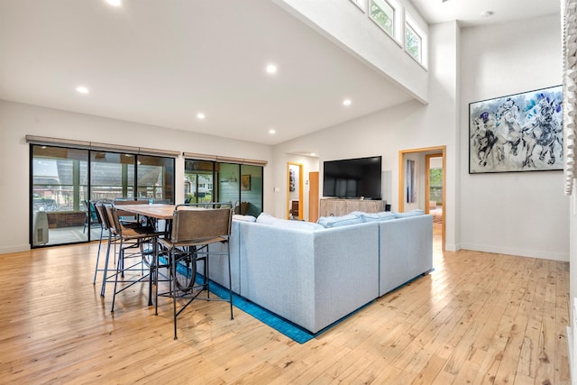 living area featuring recessed lighting, baseboards, wood-type flooring, and a towering ceiling