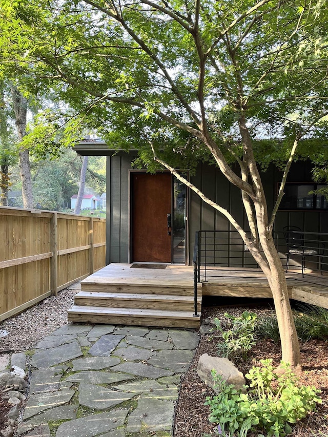 entrance to property featuring board and batten siding and fence