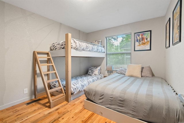 bedroom featuring visible vents, baseboards, and wood finished floors