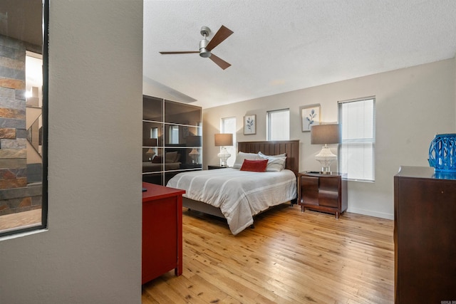 bedroom featuring light wood-style flooring, a textured ceiling, ceiling fan, and vaulted ceiling