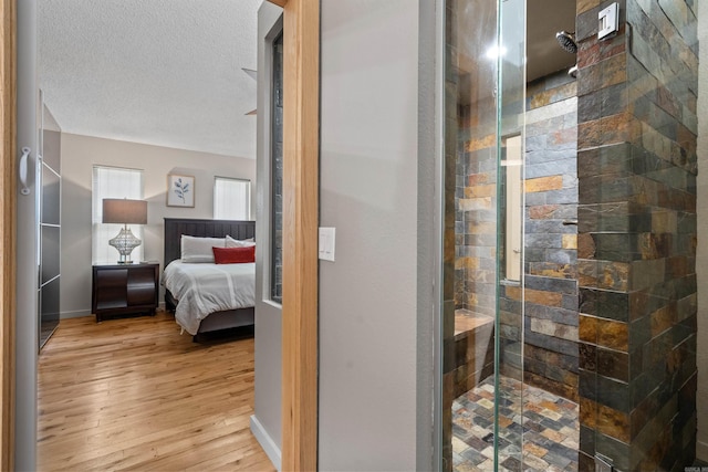 full bathroom featuring a stall shower, a textured ceiling, baseboards, and wood-type flooring