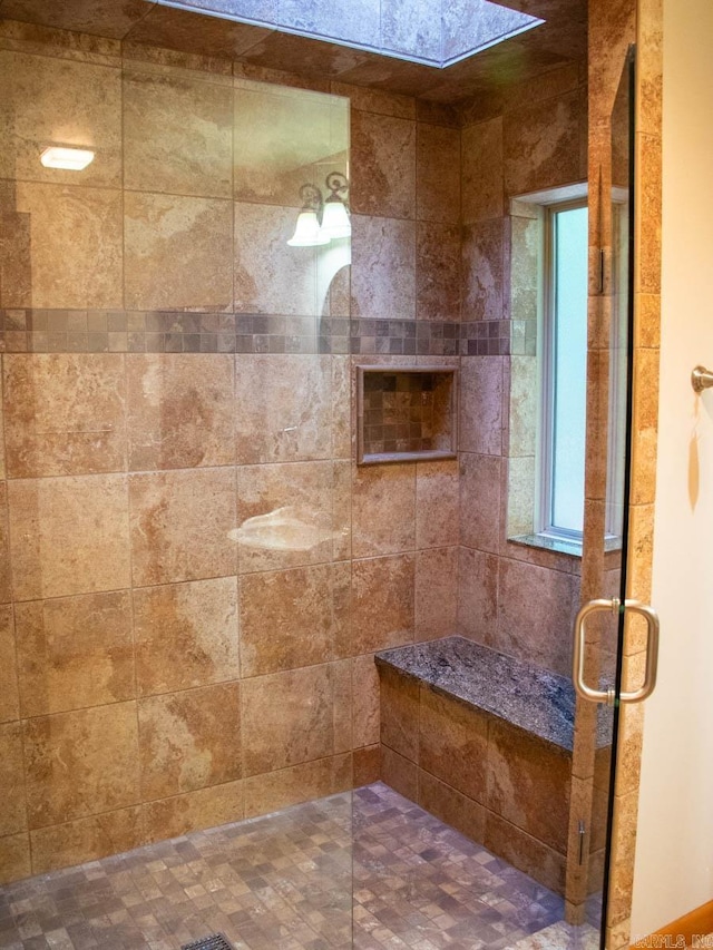 bathroom featuring a tile shower and a skylight