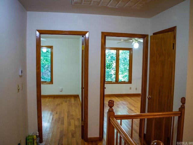 hallway featuring baseboards, an upstairs landing, and wood finished floors