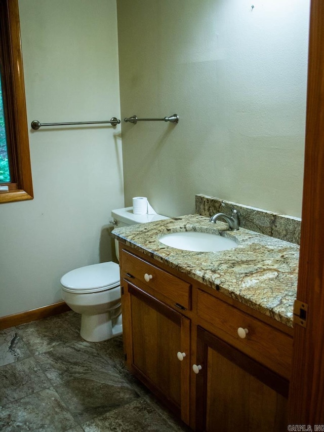 bathroom featuring toilet, vanity, and baseboards