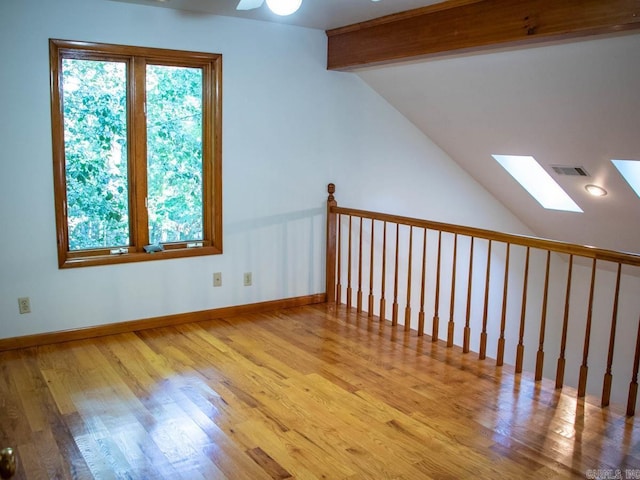 bonus room with visible vents, lofted ceiling with skylight, a healthy amount of sunlight, and wood finished floors