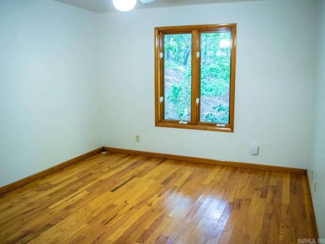 unfurnished room with baseboards, wood finished floors, and a ceiling fan