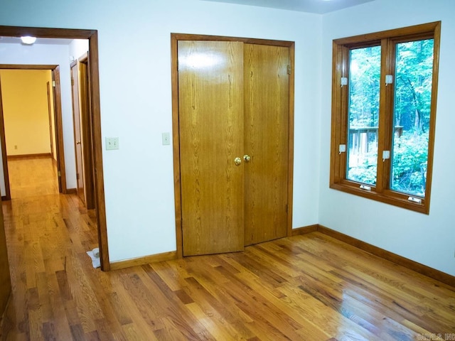 unfurnished bedroom featuring light wood-type flooring, baseboards, and a closet