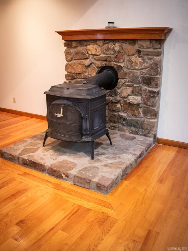 interior details with a wood stove, baseboards, and wood finished floors