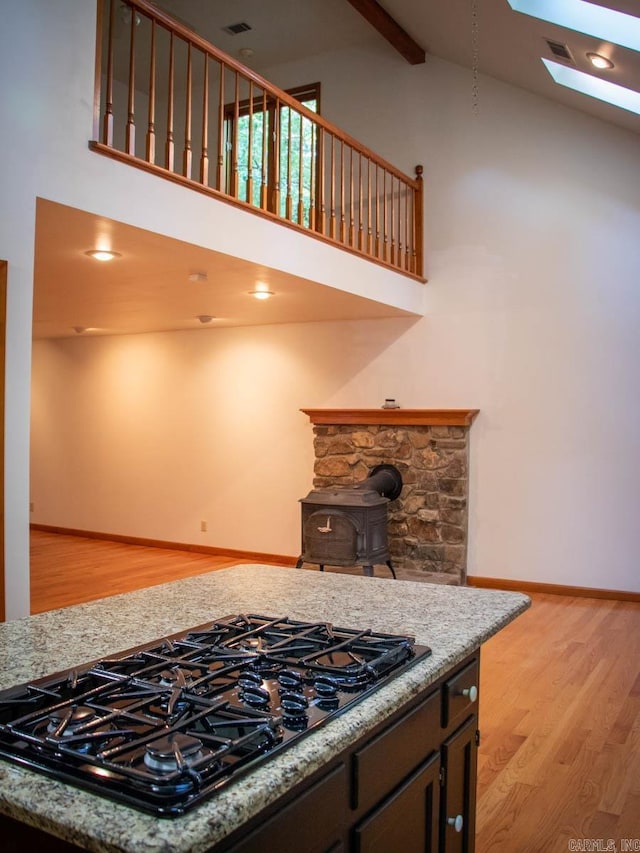 kitchen featuring beamed ceiling, light wood finished floors, high vaulted ceiling, and black gas stovetop