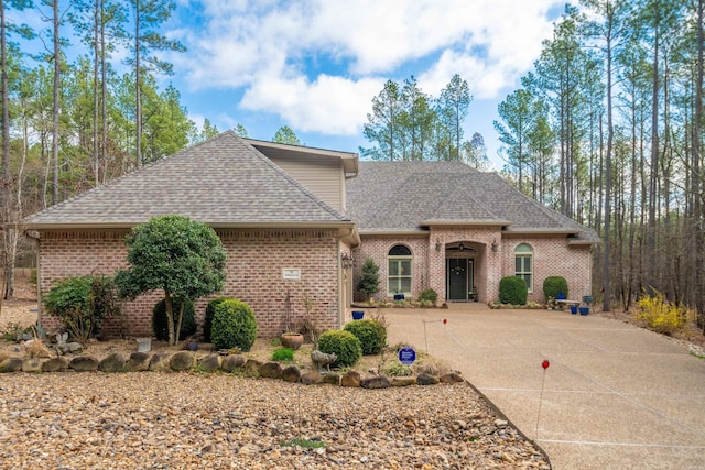 view of front facade with brick siding, concrete driveway, and a shingled roof