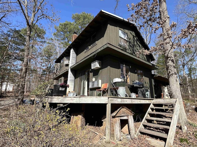 view of home's exterior with a wall mounted AC, a gambrel roof, and a chimney