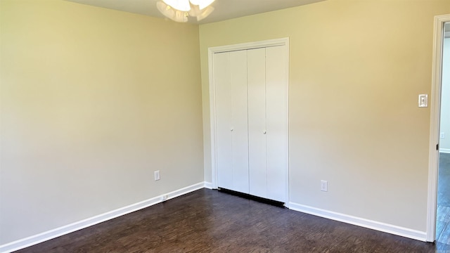 unfurnished bedroom with a closet, baseboards, and dark wood-style floors