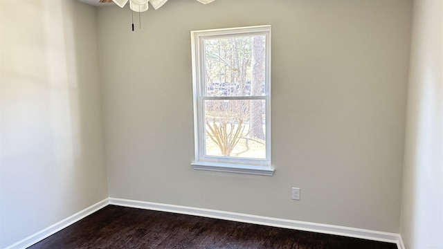 empty room with baseboards, dark wood finished floors, and a ceiling fan