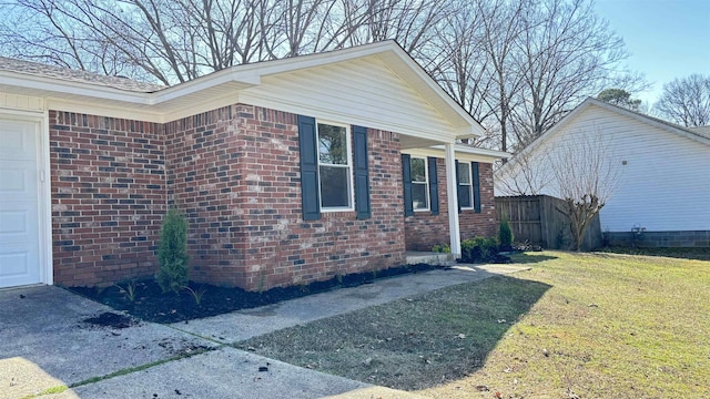 view of home's exterior featuring fence, a garage, a lawn, and brick siding