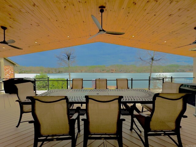 wooden terrace featuring outdoor dining area, a water view, and ceiling fan