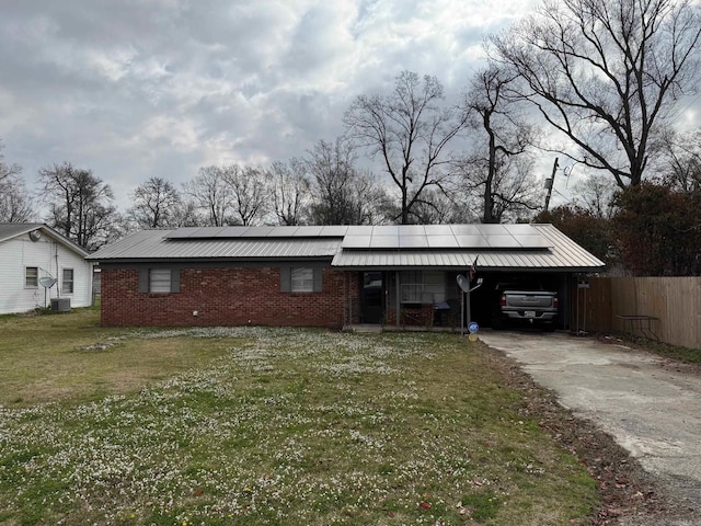 700 Thompson St, Mcgehee, AR 71654 - view of front of home with an attached carport, fence, a front yard, roof mounted solar panels, and driveway