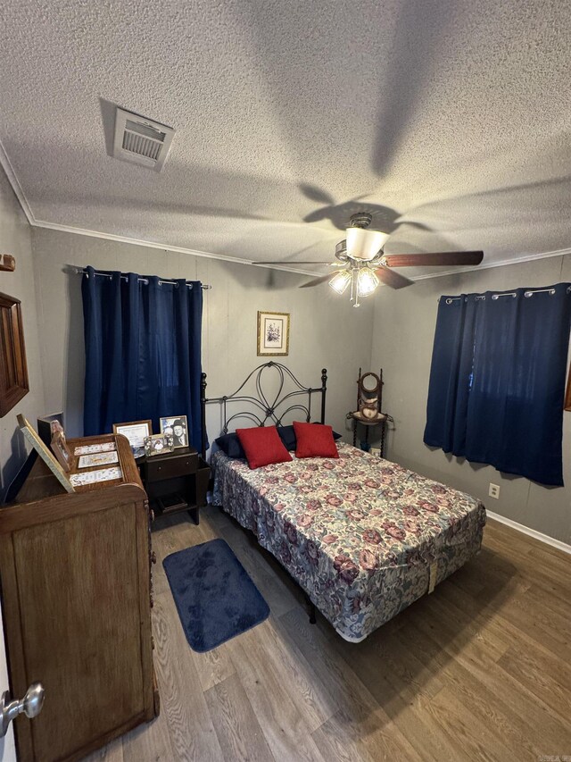 700 Thompson St, Mcgehee, AR 71654 - bedroom with visible vents, ornamental molding, wood finished floors, a textured ceiling, and a ceiling fan