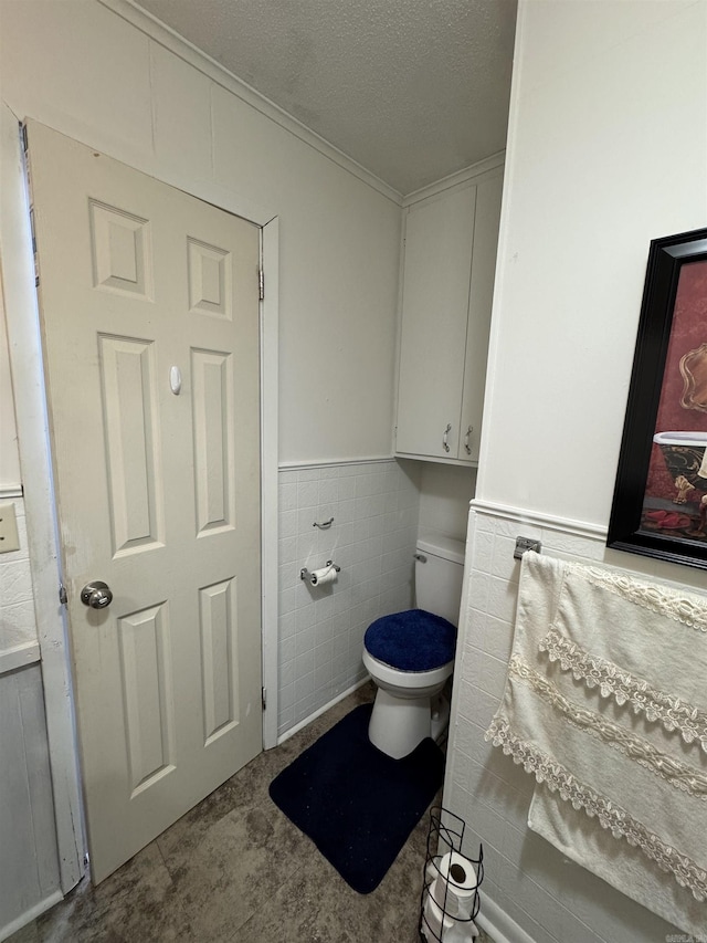 700 Thompson St, Mcgehee, AR 71654 - bathroom with toilet, tile walls, wainscoting, and a textured ceiling