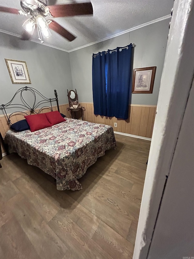 700 Thompson St, Mcgehee, AR 71654 - bedroom with wood finished floors, ornamental molding, wainscoting, a textured ceiling, and ceiling fan