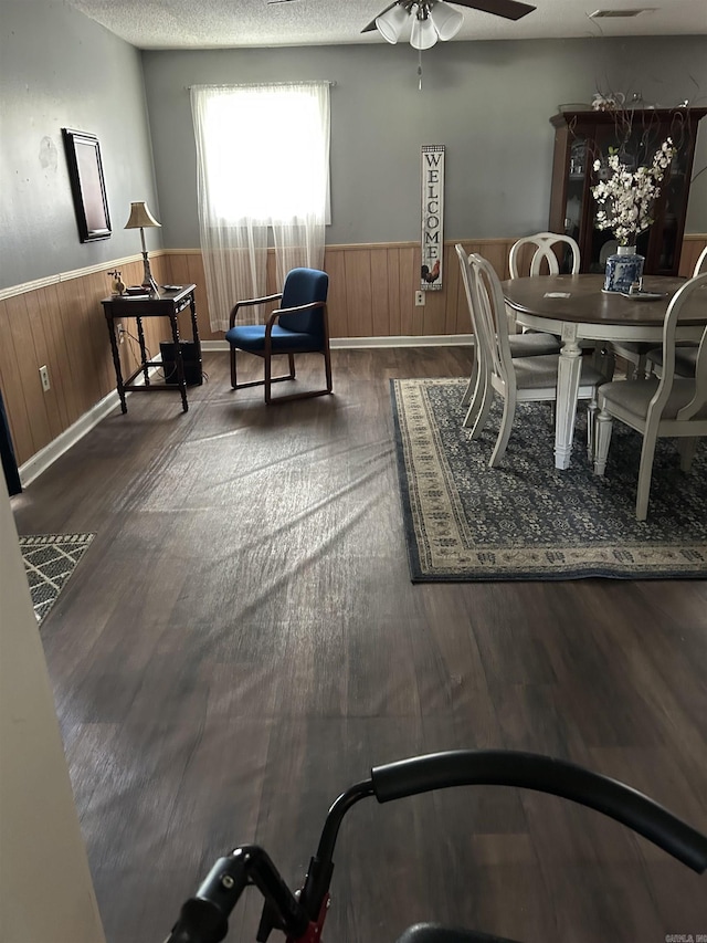 700 Thompson St, Mcgehee, AR 71654 - dining room with wainscoting, dark wood-style floors, a ceiling fan, and wooden walls