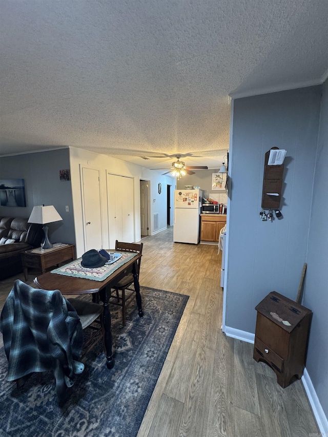 700 Thompson St, Mcgehee, AR 71654 - dining room featuring a ceiling fan, baseboards, visible vents, light wood-style flooring, and a textured ceiling