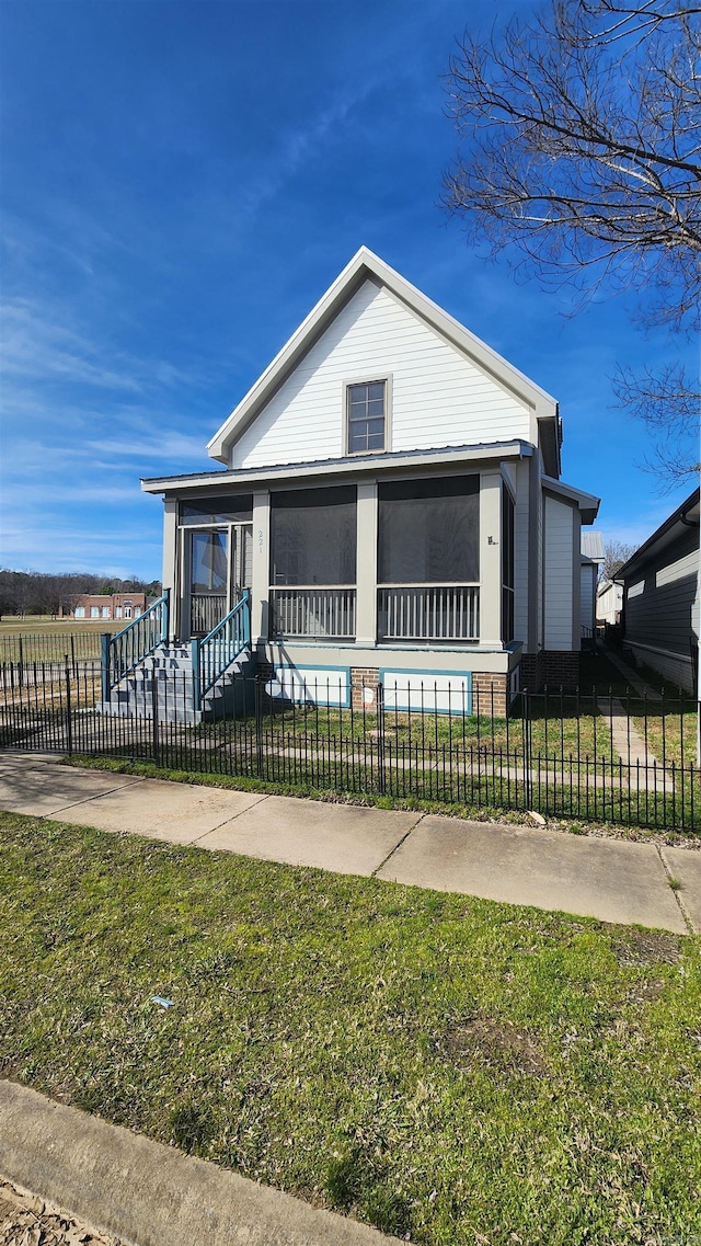 view of front facade with a fenced front yard, a front yard, and a sunroom