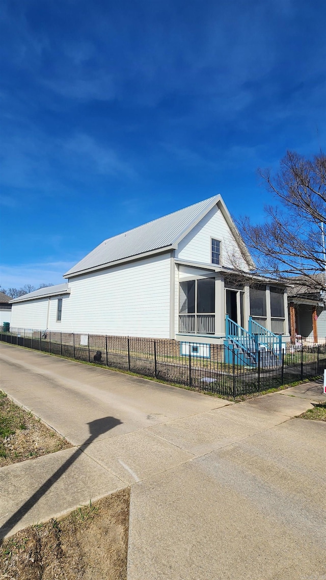 view of side of property featuring metal roof and fence