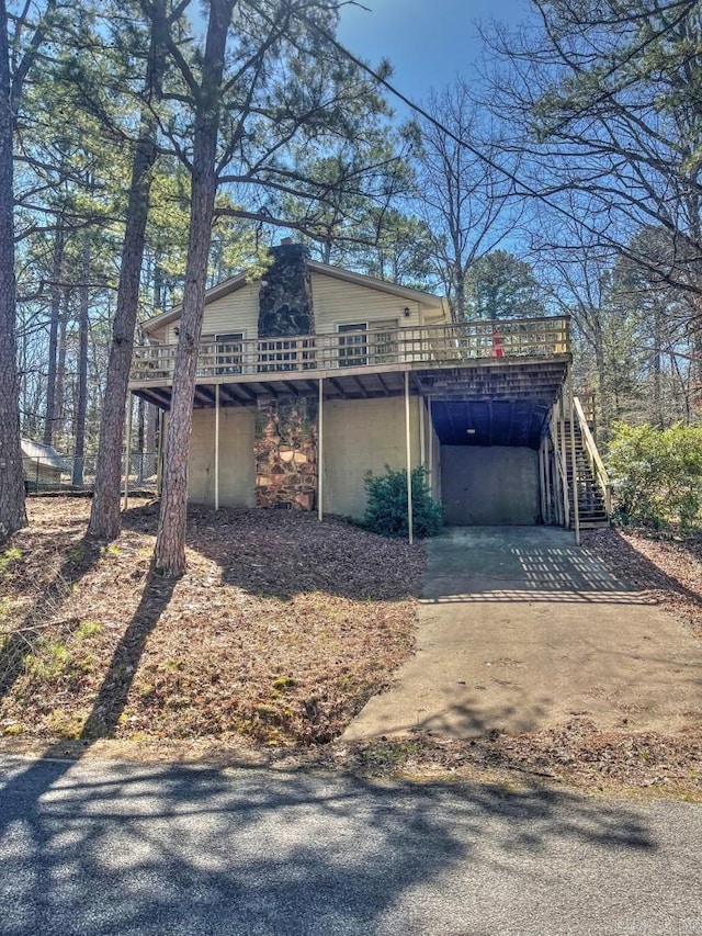 view of side of property featuring an attached carport, driveway, a wooden deck, and stairs