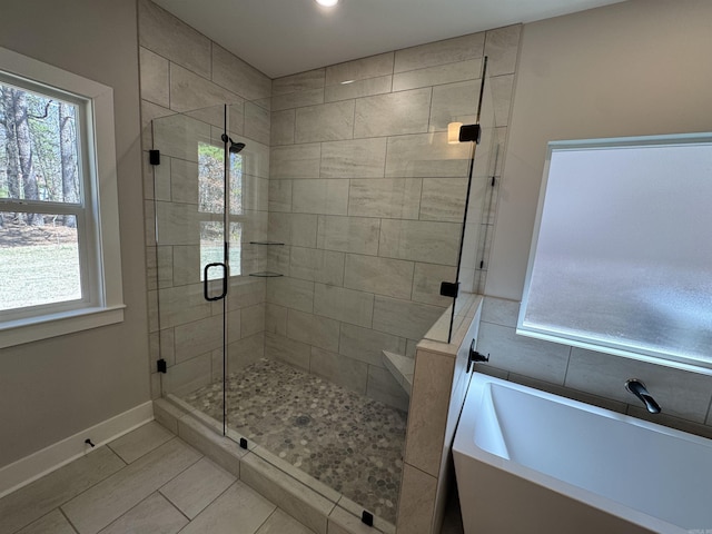 full bath with a shower stall, a bath, and baseboards