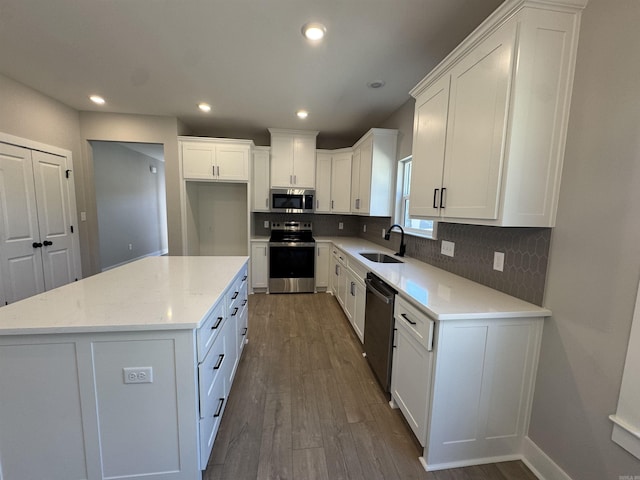 kitchen with dark wood finished floors, white cabinetry, stainless steel appliances, and a sink