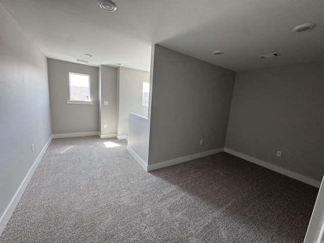 carpeted empty room featuring visible vents and baseboards