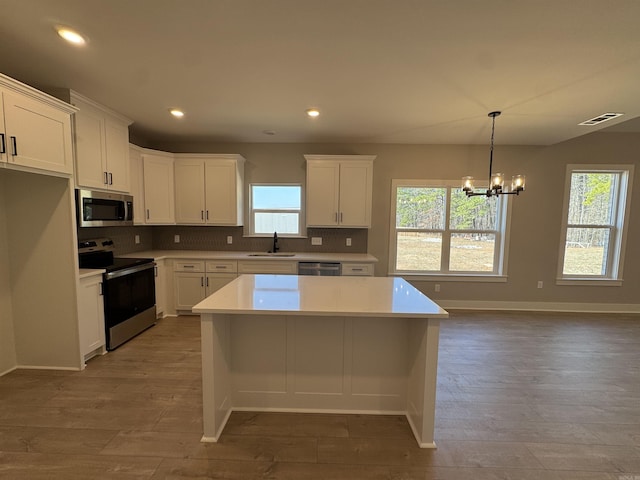 kitchen with tasteful backsplash, visible vents, appliances with stainless steel finishes, a notable chandelier, and a sink