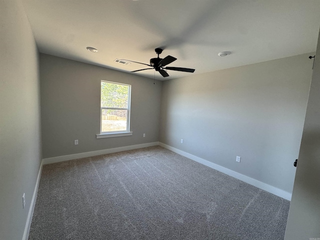 carpeted spare room with visible vents, baseboards, and a ceiling fan