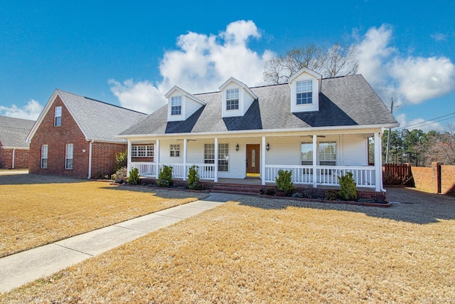 cape cod-style house with a porch, a front lawn, and a shingled roof