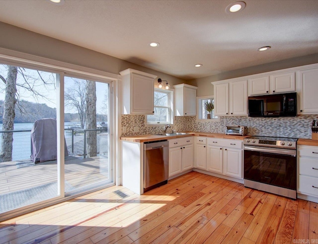kitchen featuring white cabinetry, light wood-style flooring, tasteful backsplash, and stainless steel appliances
