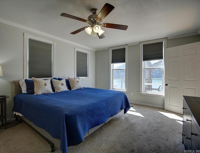 carpeted bedroom with ceiling fan, a textured ceiling, baseboards, and ornamental molding