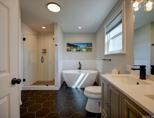 bathroom featuring double vanity, a stall shower, a freestanding bath, a sink, and tile patterned floors