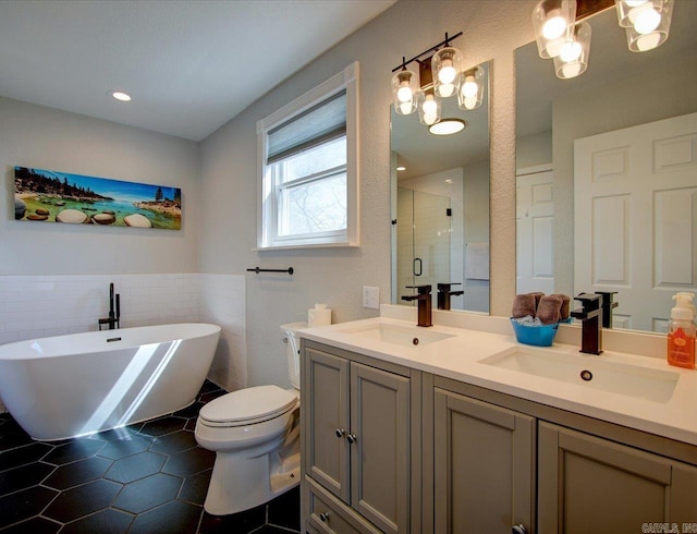 bathroom featuring tile patterned floors, a stall shower, double vanity, and a sink