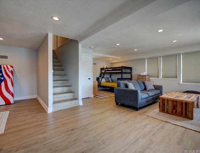 living room featuring stairway, wood finished floors, baseboards, recessed lighting, and a textured ceiling