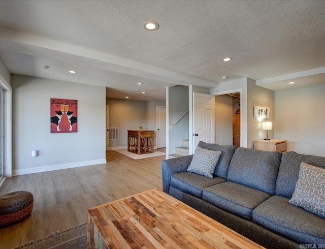 living room with visible vents, a textured ceiling, wood finished floors, recessed lighting, and stairway
