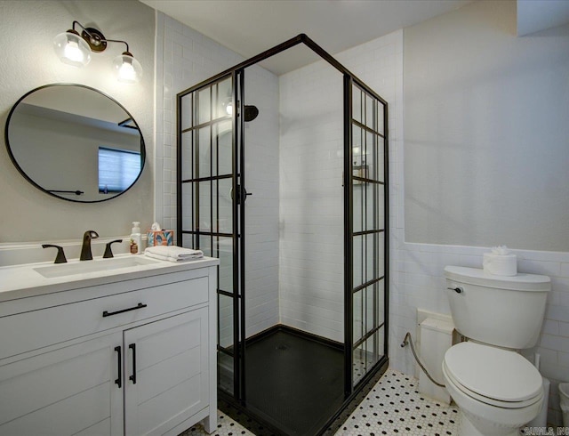 bathroom with vanity, a wainscoted wall, a shower stall, tile walls, and toilet
