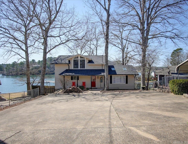view of front of property featuring fence, a water view, and roof with shingles