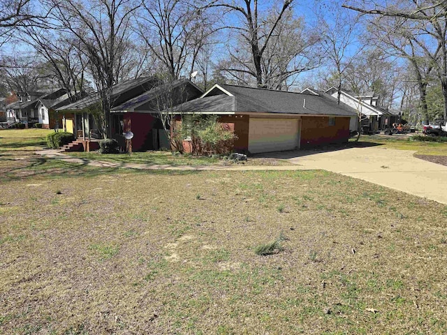 view of side of home with concrete driveway, an attached garage, and a lawn