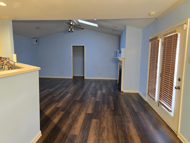 unfurnished living room featuring dark wood finished floors, baseboards, ceiling fan, and vaulted ceiling