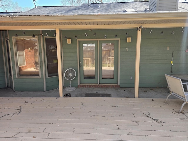 doorway to property featuring a wooden deck, roof with shingles, and a chimney